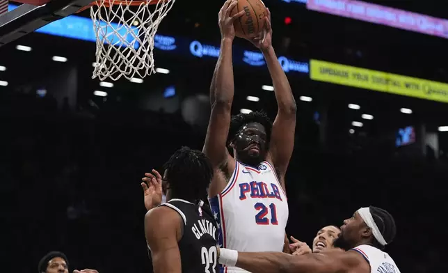 Philadelphia 76ers' Joel Embiid fights for control of the ball with Brooklyn Nets' Nic Claxton (33) during the first half of an NBA basketball game Saturday, Jan. 4, 2025, in New York. (AP Photo/Frank Franklin II)