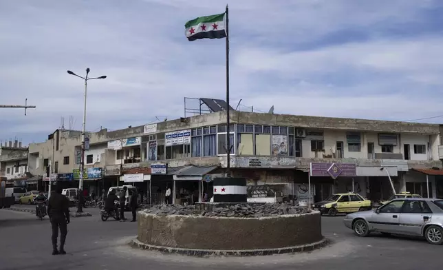 Cars drive past a roundabout hoisting the new Syrian flag after the ousting of the Assad regime, in Salam City, formerly called Baath City after the ruling party, in Quneitra, Syria, Sunday, Jan. 5, 2025. (AP Photo/Mosa'ab Elshamy)