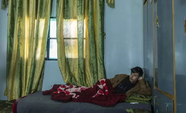 Abdelrahman Khaled al-Aqqad, 18, lies on a bed in his home after getting shot in both legs by the the Israeli military at a protest against their incursion into his village of Dawaya, on the outskirts of Quneitra, Syria, Sunday, Jan. 5, 2025. (AP Photo/Mosa'ab Elshamy)