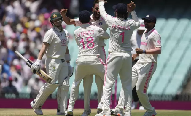 Indian players celebrate the dismissal of Australia's Steve Smith, left, during play on the third day of the fifth cricket test between India and Australia at the Sydney Cricket Ground, in Sydney, Australia, Sunday, Jan. 5, 2025. (AP Photo/Mark Baker)