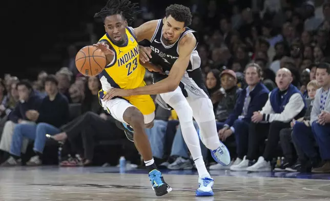 San Antonio Spurs center Victor Wembanyama (1) and Indiana Pacers forward Aaron Nesmith (23) get tangled up as they go for a loose ball during the second half of a Paris Games 2025 NBA basketball game in Paris, Saturday, Jan. 25, 2025. (AP Photo/Thibault Camus)