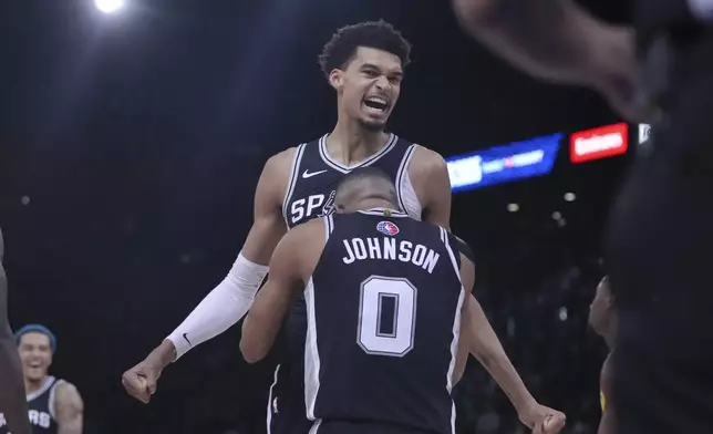 San Antonio Spurs center Victor Wembanyama, top, celebrates with forward Keldon Johnson (0) during the second half of a Paris Games 2025 NBA basketball game against the Indiana Pacers in Paris, Thursday, Jan. 23, 2025. (AP Photo/Thibault Camus)