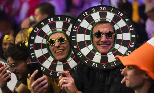 Fans dressed in costumes wait for the start of the round 4 match between Ricardo Pietreczko of Germany and Nathan Aspinall of England at the World Darts Championship in London, Monday, Dec. 30, 2024. (AP Photo/Alberto Pezzali)