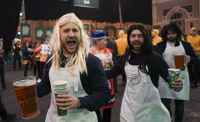 Fans dressed in costumes arrive for the start of the round 4 match between Kevin Doets of the Netherlands and Chris Dobey of England at the World Darts Championship in London, Monday, Dec. 30, 2024. (AP Photo/Alberto Pezzali)