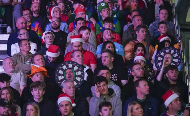 Fans dressed in costumes attend the round 4 match between Kevin Doets of the Netherlands and Chris Dobey of England at the World Darts Championship in London, Monday, Dec. 30, 2024. (AP Photo/Alberto Pezzali)