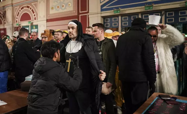 Fans dressed in costumes are seen around the fan village before the start of the quarter final match between Peter Wright of Scotland and Stephen Bunting of England, at the World Darts Championship in London, Wednesday, Jan. 1, 2025.(AP Photo/Alberto Pezzali)