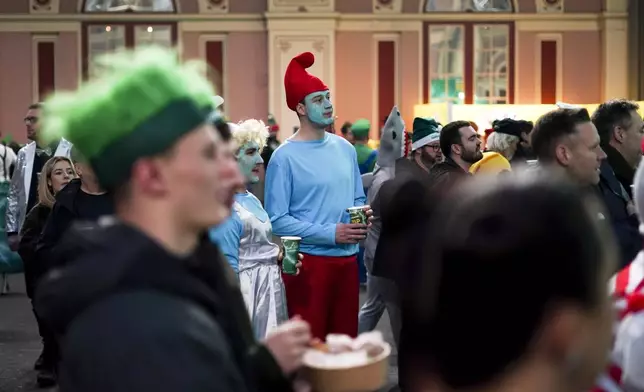 Fans dressed in costumes arrive for the start of the quarter final match between Chris Dobey of England and Gerwin Price of Wales at the World Darts Championship in London, Wednesday, Jan. 1, 2025. (AP Photo/Alberto Pezzali)