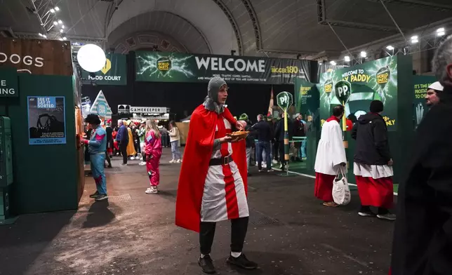 Fans dressed in costumes are seen around the fan village before the start of the quarter final match between Peter Wright of Scotland and Stephen Bunting of England, at the World Darts Championship in London, Wednesday, Jan. 1, 2025.(AP Photo/Alberto Pezzali)
