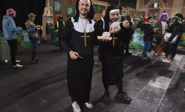 Fans dressed in costumes are seen around the fan village before the start of the semifinal match between Michael van Gerwen of the Netherlands and Chris Dobey of England, at the World Darts Championship in London, Thursday, Jan. 2, 2025. (AP Photo/Kirsty Wigglesworth)