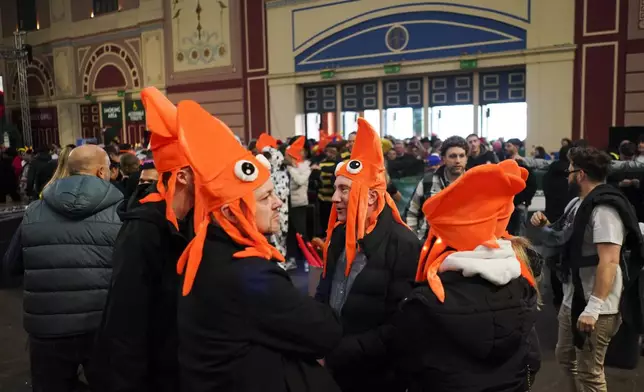 Fans dressed in costumes arrive for the start of the round 4 match between Kevin Doets of the Netherlands and Chris Dobey of England at the World Darts Championship in London, Monday, Dec. 30, 2024. (AP Photo/Alberto Pezzali)