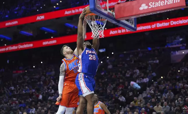 Philadelphia 76ers' Guerschon Yabusele, right, dunks past Oklahoma City Thunder's Isaiah Hartenstein during the first half of an NBA basketball game, Tuesday, Jan. 14, 2025, in Philadelphia. (AP Photo/Matt Slocum)