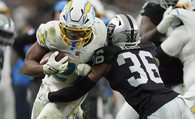 Los Angeles Chargers running back J.K. Dobbins, left, runs against Las Vegas Raiders cornerback Kyu Blu Kelly (36) during the second half of an NFL football game in Las Vegas, Sunday, Jan. 5, 2025. (AP Photo/John Locher)