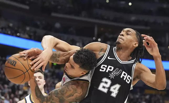 Denver Nuggets forward Michael Porter Jr., left, battles for control of a rebound with San Antonio Spurs guard Devin Vassell in the first half of an NBA basketball game Friday, Jan. 3, 2025, in Denver. (AP Photo/David Zalubowski)