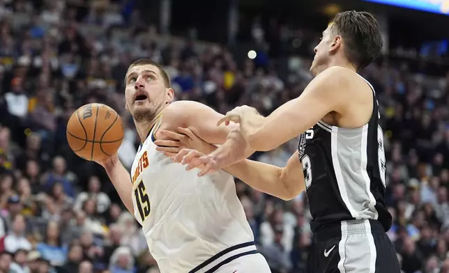 Denver Nuggets center Nikola Jokic, left, drives to the basket as San Antonio Spurs forward Zach Collins defends in the first half of an NBA basketball game Friday, Jan. 3, 2025, in Denver. (AP Photo/David Zalubowski)