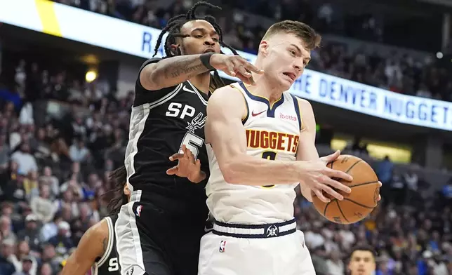 Denver Nuggets guard Christian Braun, right, pulls in a rebound as San Antonio Spurs guard Stephon Castle defends in the first half of an NBA basketball game Friday, Jan. 3, 2025, in Denver. (AP Photo/David Zalubowski)