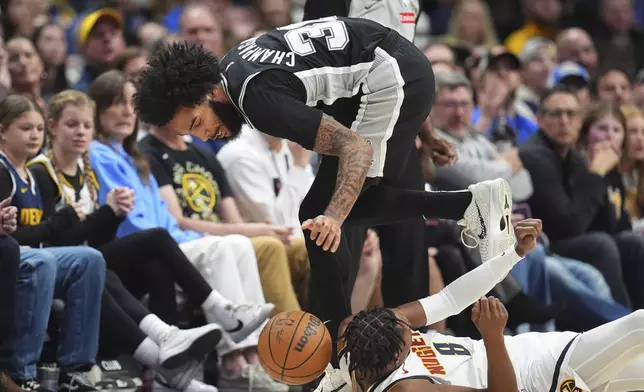 San Antonio Spurs forward Julian Champagnie, top, collects the ball as Denver Nuggets forward Peyton Watson, bottom, tumbles to the floor in the first half of an NBA basketball game Friday, Jan. 3, 2025, in Denver. (AP Photo/David Zalubowski)