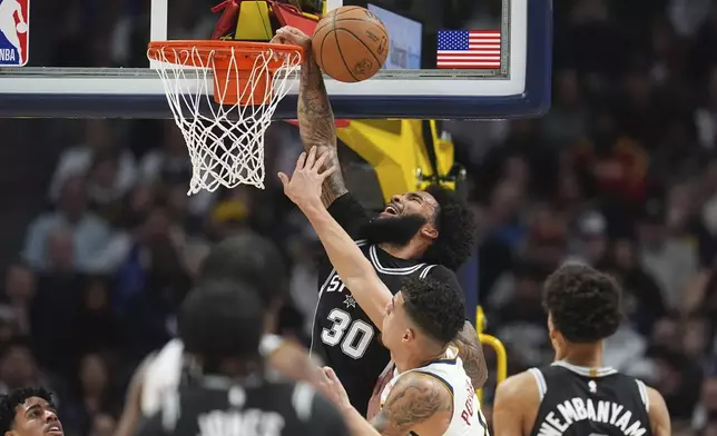 Denver Nuggets forward Michael Porter Jr., front, blocks a shot by San Antonio Spurs forward Julian Champagnie in the first half of an NBA basketball game Friday, Jan. 3, 2025, in Denver. (AP Photo/David Zalubowski)