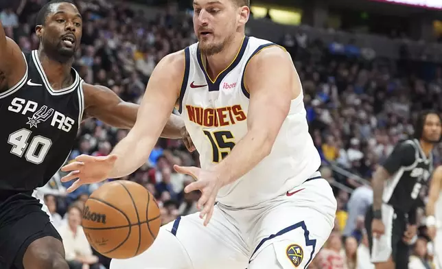 Denver Nuggets center Nikola Jokic, front, collects a loose ball as San Antonio Spurs forward Harrison Barnes defends in the first half of an NBA basketball game Friday, Jan. 3, 2025, in Denver. (AP Photo/David Zalubowski)