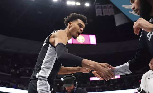 San Antonio Spurs center Victor Wembanyama, left, greets forward Julian Champagnie, right, while taking the court for an NBA basketball game against the Denver Nuggets, Friday, Jan. 3, 2025, in Denver. (AP Photo/David Zalubowski)