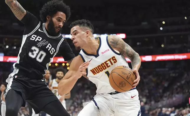 Denver Nuggets forward Michael Porter Jr., right, drives to the basket as San Antonio Spurs forward Julian Champagnie defends in the first half of an NBA basketball game Friday, Jan. 3, 2025, in Denver. (AP Photo/David Zalubowski)