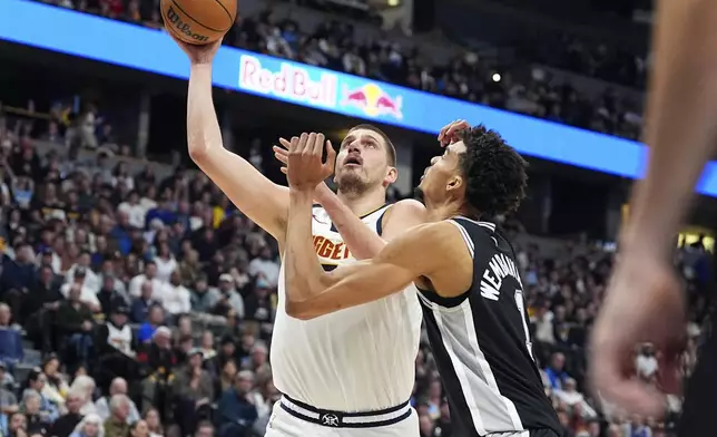 Denver Nuggets center Nikola Jokic, left, goes up for a basket as San Antonio Spurs center Victor Wembanyama defends in the first half of an NBA basketball game Friday, Jan. 3, 2025, in Denver. (AP Photo/David Zalubowski)