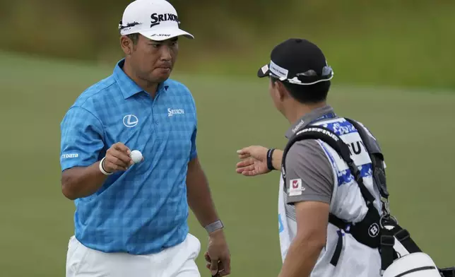 Hideki Matsuyama, of Japan,, left, hands his ball to his caddie on the 12th green during the first round of The Sentry golf event, Thursday, Jan. 2, 2025, at Kapalua Plantation Course in Kapalua, Hawaii. (AP Photo/Matt York)