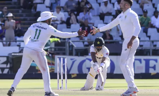 South Africa's Temba Bavuma (c), left congratulates South Africa's Keshav Maharaj for the wicket of Pakistan's Aamir Jamal during the fourth day of the second test match between South Africa and Pakistan in Cape Town, South Africa, Monday, Jan. 6, 2025. (AP Photo/Halden Krog)