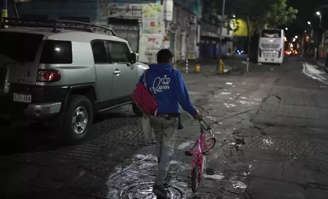 A person walks with a bicycle donated by volunteers who call themselves the Punk Kings after they distributed toys, clothes and pinatas to underprivileged children at a migrant shelter on the occasion of the Epiphany, or Three Kings Day, in Mexico City, early Monday, Jan. 6, 2025. (AP Photo/Eduardo Verdugo)