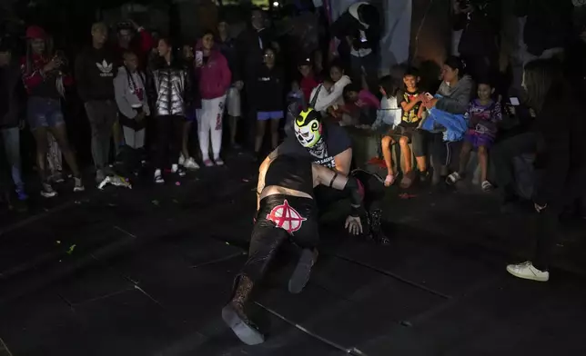 Migrants watch Lucha Libre wrestlers perform, organised by volunteers who call themselves the Punk Kings as they distribute toys, clothes and pinatas to underprivileged children at a migrant shelter on the occasion of the Epiphany, or Three Kings Day, in Mexico City, early Monday, Jan. 6, 2025. (AP Photo/Eduardo Verdugo)