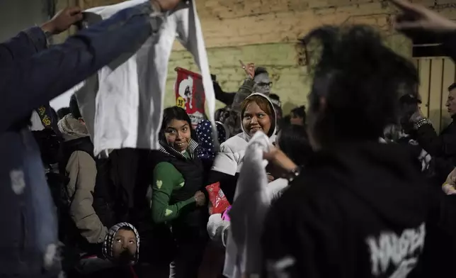 Neighbors watch clothes donated by volunteers who call themselves the Punk Kings as they distribute toys, clothes and pinatas to underprivileged children on the occasion of the Epiphany, or Three Kings Day, celebration in Mexico City, Sunday, Jan. 5, 2025. (AP Photo/Eduardo Verdugo)