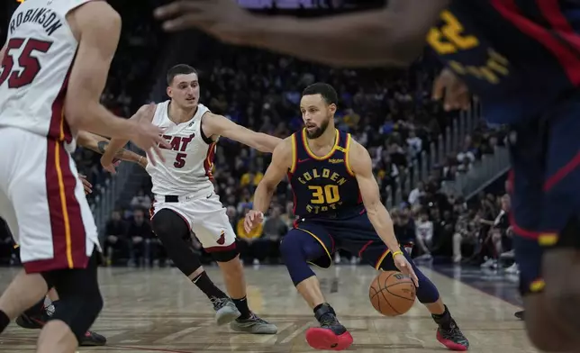 Golden State Warriors guard Stephen Curry (30) moves the ball while defended by Miami Heat forward Nikola Jovic (5) during the second half of an NBA basketball game Tuesday, Jan. 7, 2025, in San Francisco. (AP Photo/Godofredo A. Vásquez)