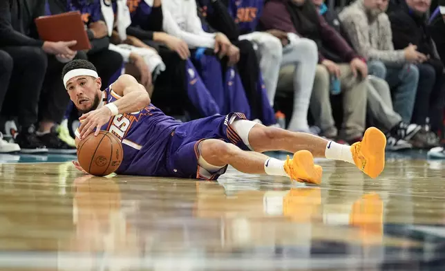 Phoenix Suns guard Devin Booker grabs a loose ball against the Charlotte Hornets during the first half of an NBA basketball game in Charlotte, N.C., Tuesday, Jan. 7, 2025. (AP Photo/Jim Dedmon)