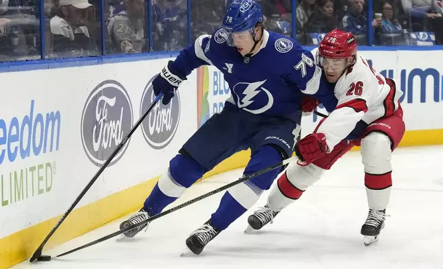 Tampa Bay Lightning defenseman Emil Lilleberg (78) keeps the puck from Carolina Hurricanes defenseman Sean Walker (26) during the second period of an NHL hockey game Tuesday, Jan. 7, 2025, in Tampa, Fla. (AP Photo/Chris O'Meara)