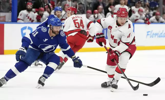 Carolina Hurricanes center Jack Drury (18) carries the puck in front of Tampa Bay Lightning center Luke Glendening (11) during the second period of an NHL hockey game Tuesday, Jan. 7, 2025, in Tampa, Fla. (AP Photo/Chris O'Meara)