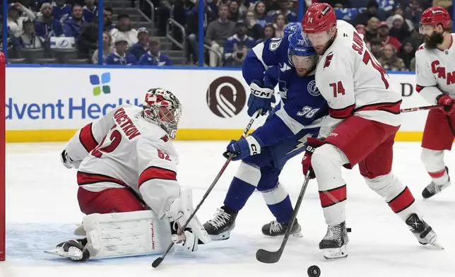 Carolina Hurricanes defenseman Jaccob Slavin (74) keeps Tampa Bay Lightning left wing Brandon Hagel (38) from the puck after a save by Hurricanes goaltender Pyotr Kochetkov (52) during the second period of an NHL hockey game Tuesday, Jan. 7, 2025, in Tampa, Fla. (AP Photo/Chris O'Meara)