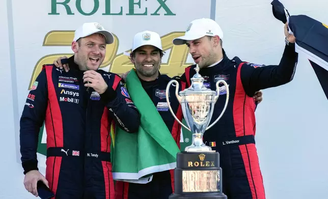 Porsche Penske Motorsport team members, from left to right, Britain's Nick Tandy, Brazil's Felipe Nasr and Belgium's Laurens Vanthoor celebrate after winning the IMSA Rolex 24 hour auto race at Daytona International Speedway, Sunday, Jan. 26, 2025, in Daytona Beach, Fla. (AP Photo/John Raoux)