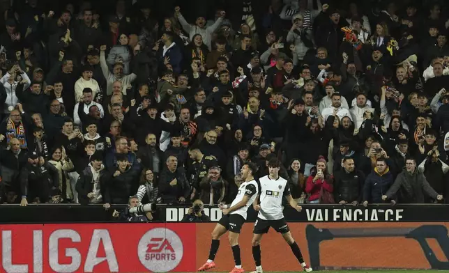 Valencia's Hugo Duro, left, celebrates after scoring the opening goal against Real Madrid during a Spanish La Liga soccer match at Mestalla stadium in Valencia, Spain, Friday, Jan. 3, 2025. (AP Photo/Alberto Saiz)