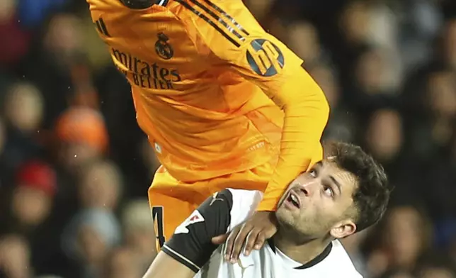 Real Madrid's Aurelien Tchouameni, top, heads the ball next to Valencia's Hugo Duro during a Spanish La Liga soccer match at Mestalla stadium in Valencia, Spain, Friday, Jan. 3, 2025. (AP Photo/Alberto Saiz)