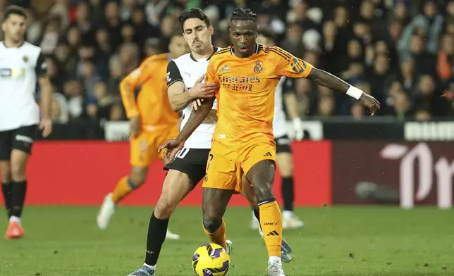 Real Madrid's Vinicius Junior, front, and Valencia's Andre Almeida battle for the ball during a Spanish La Liga soccer match at Mestalla stadium in Valencia, Spain, Friday, Jan. 3, 2025. (AP Photo/Alberto Saiz)