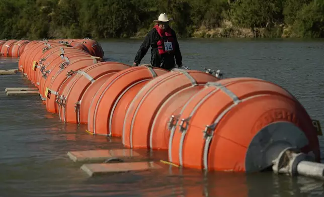 FILE - A kayaker walks past large buoys being used as a floating border barrier on the Rio Grande, Aug. 1, 2023, in Eagle Pass, Texas. (AP Photo/Eric Gay, File)