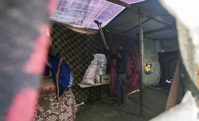 A man removes water from the fabric roof of a makeshift tent following overnight rainfall at the refugee tent camp for displaced Palestinians in Deir al-Balah, central Gaza Strip, Tuesday, Dec. 31, 2024. (AP Photo/Abdel Kareem Hana)