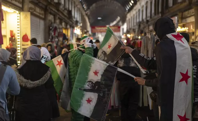 A vendor sells new Syrian flags in Al-Hamidiyeh Souq on New Years Eve, in Damascus, Syria, Tuesday, Dec. 31, 2024. (AP Photo/Mosa'ab Elshamy)