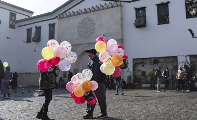 Balloon sellers wait for customers near Al-Hamidiyeh Souq on New Years Eve, in Damascus, Syria, Tuesday, Dec. 31, 2024. (AP Photo/Mosa'ab Elshamy)