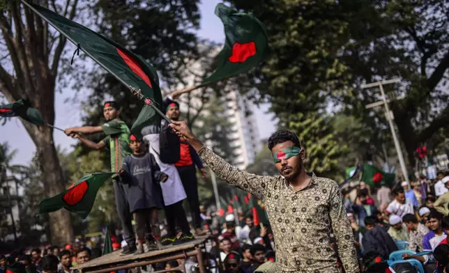 Participants wave Bangladesh national flags during "March for Unity" organized by The Anti-Discrimination Student Movement at the Central Shaheed Minar, a national monument, in Dhaka, Bangladesh, Tuesday, Dec. 31, 2024. (AP Photo/Mahmud Hossain Opu)