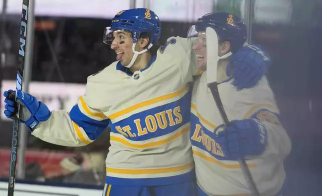 St. Louis Blues center Jordan Kyrou (25), left, and center Dylan Holloway (81) celebrate Holloway's goal on the Chicago Blackhawks during the second period of the NHL Winter Classic outdoor hockey game at Wrigley Field, Tuesday, Dec. 31, 2024, in Chicago. (AP Photo/Erin Hooley)