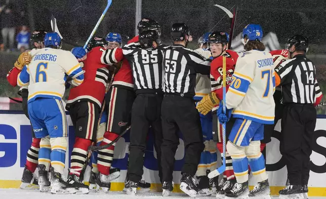 Officials break up a fight between the St. Louis Blues and Chicago Blackhawks during the second period of the NHL Winter Classic outdoor hockey game at Wrigley Field, Tuesday, Dec. 31, 2024, in Chicago. (AP Photo/Erin Hooley)