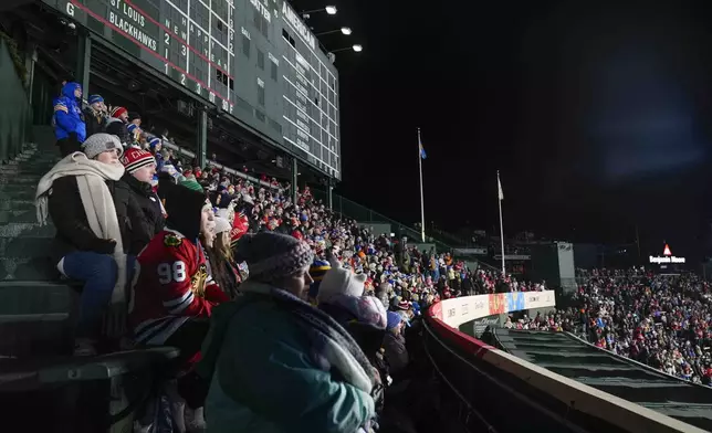 Fans watch the third period of the NHL Winter Classic outdoor hockey game featuring the Chicago Blackhawks and the St. Louis Blues from the bleachers at Wrigley Field, Tuesday, Dec. 31, 2024, in Chicago. (AP Photo/Erin Hooley)