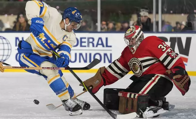 Chicago Blackhawks goaltender Petr Mrazek (34) makes a save against St. Louis Blues center Brayden Schenn, left, during the second period of the NHL Winter Classic outdoor hockey game at Wrigley Field, Tuesday, Dec. 31, 2024, in Chicago. (AP Photo/Erin Hooley)