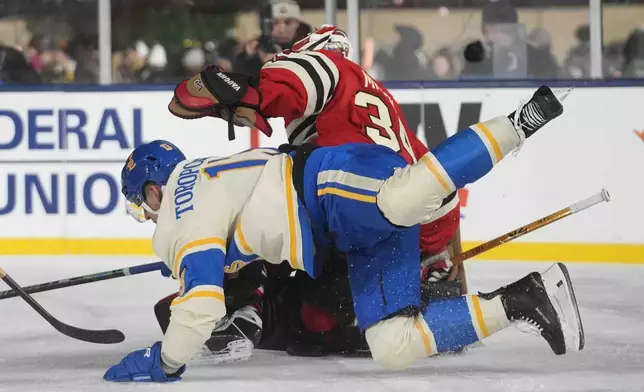 St. Louis Blues right wing Alexey Toropchenko (13) gets a goalie interference call as he crashes into Chicago Blackhawks goaltender Petr Mrazek (34) during the second period of the NHL Winter Classic outdoor hockey game at Wrigley Field, Tuesday, Dec. 31, 2024, in Chicago. (AP Photo/Erin Hooley)