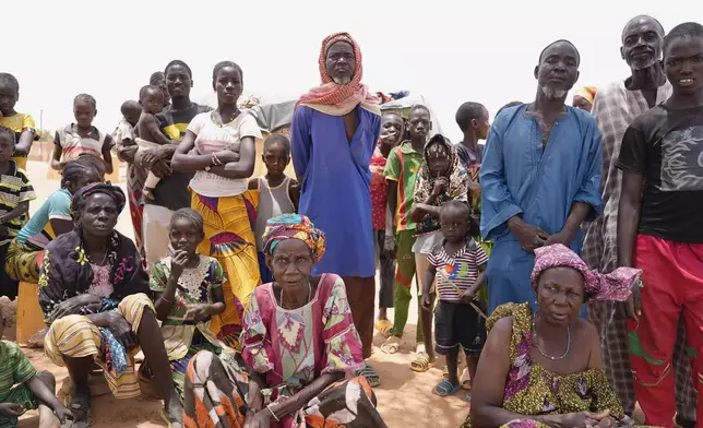 FILE - Internally displaced people wait for aid in Djibo, Burkina Faso, May 26, 2022, when violence linked to al-Qaida and the Islamic State group began surging and spreading across the West African nation. (AP Photo/Sam Mednick, File)